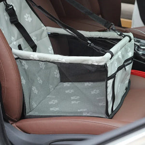 Gray paw print pet car booster seat with mesh sides and safety straps installed on car seat